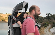 Tommy, tired by his fathers hiking uphill, has settled down to sleep on his back